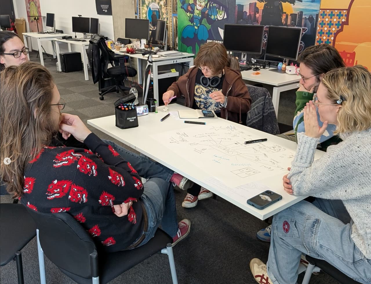 Students sat around a table in the studio working through a design exercise on paper.